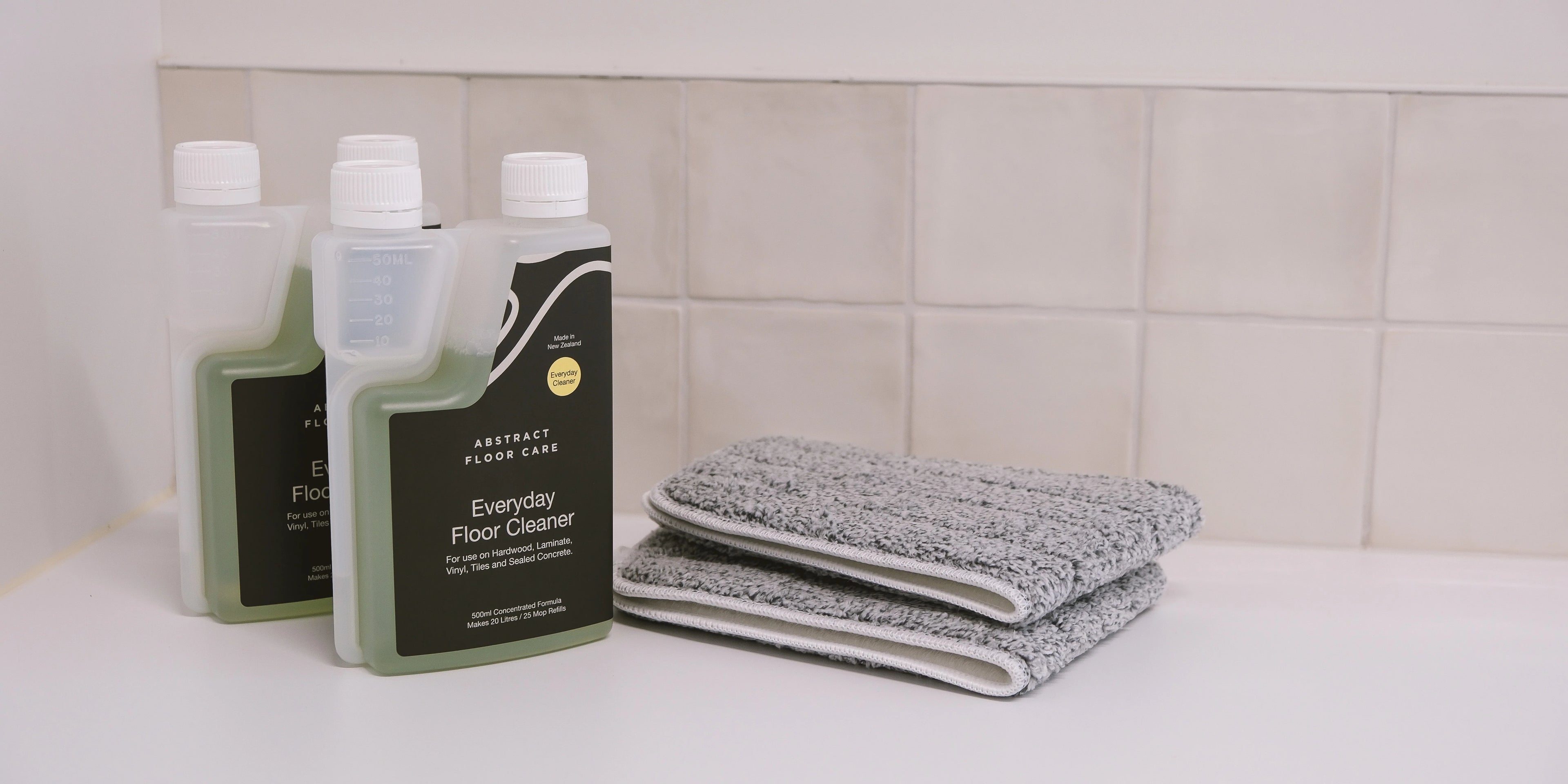 Bottle of pH-neutral laminate floor cleaner beside a spray mop on clean, streak-free laminate flooring