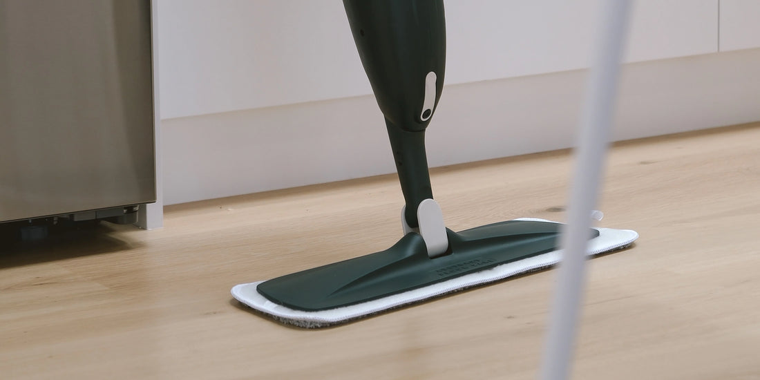 Person damp mopping sealed hardwood timber floors with a spray mop in a bright New Zealand home interior