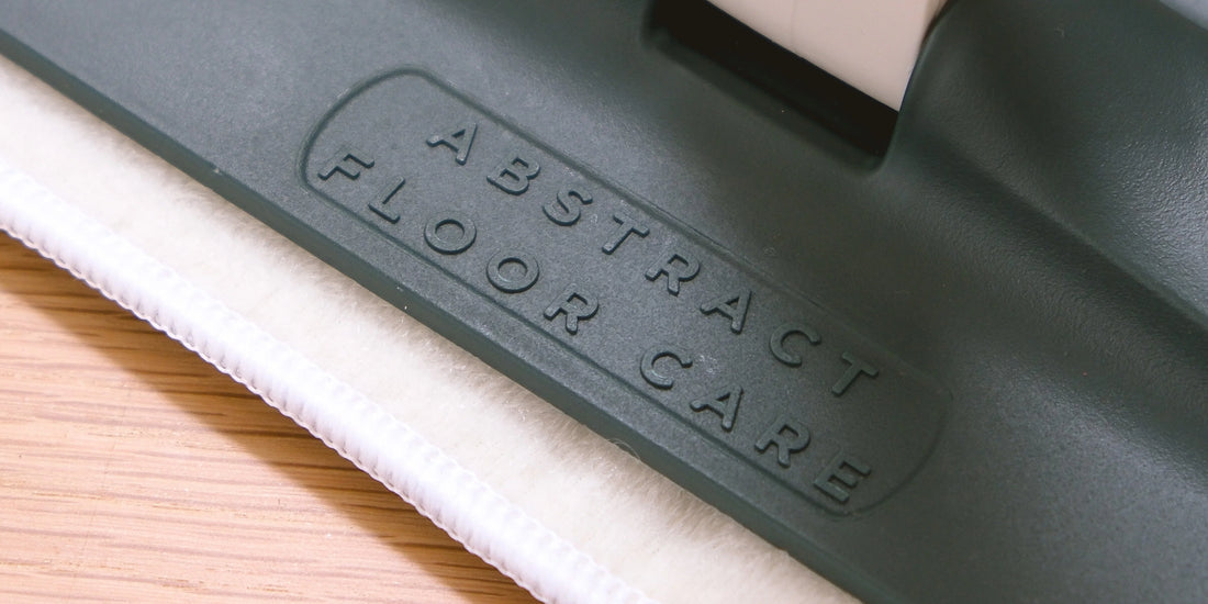 Person damp mopping a clean vinyl plank floor with a spray mop and microfibre head in a modern home